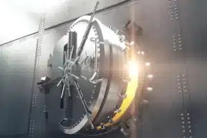 A bank vault being open with gold light shining through the crack