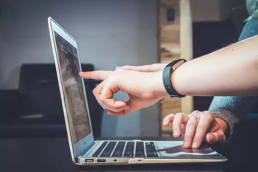 People pointing at a computer screen while looking at their infinite banking policy online.