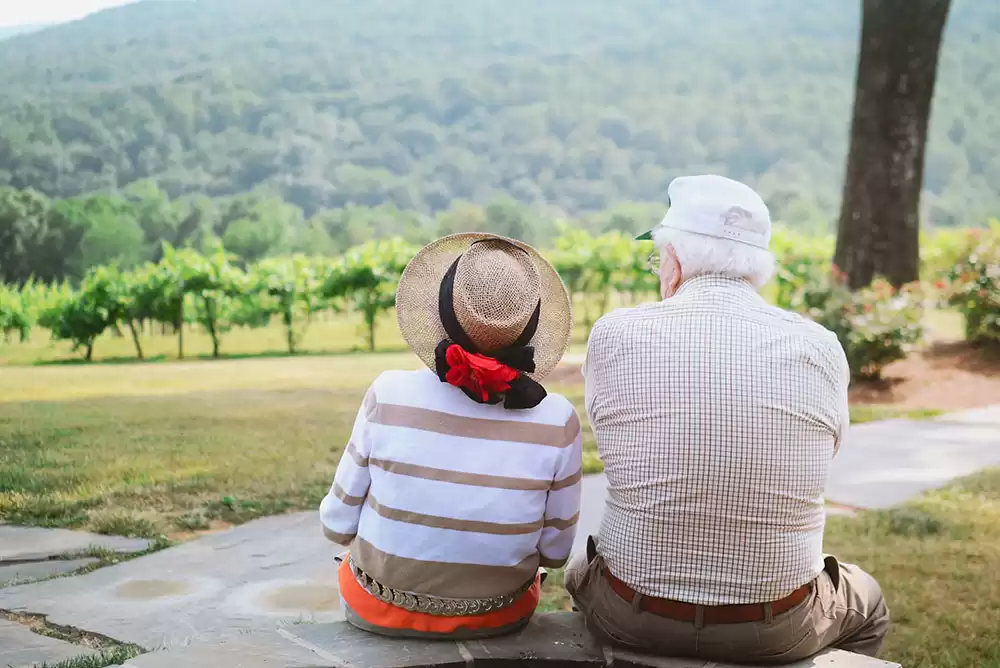 An elderly couple sitting down outside discussing life insurance retirement planning.