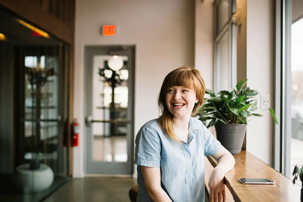 A happy, smiling woman sitting in a coffee shop.
