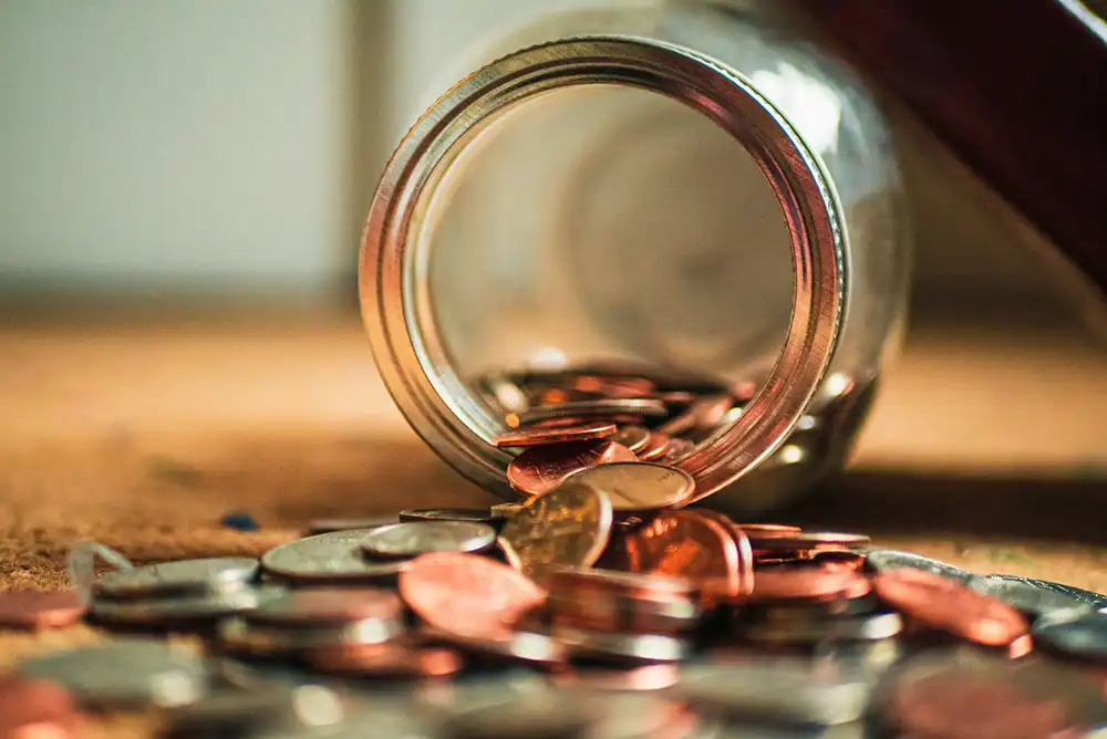 Coins spilling out of a mason jar on a table