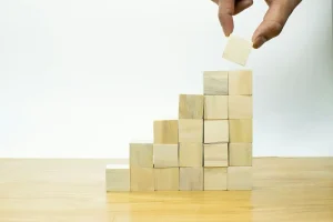 a person is placing wooden blocks on top of an inclined step pyramid