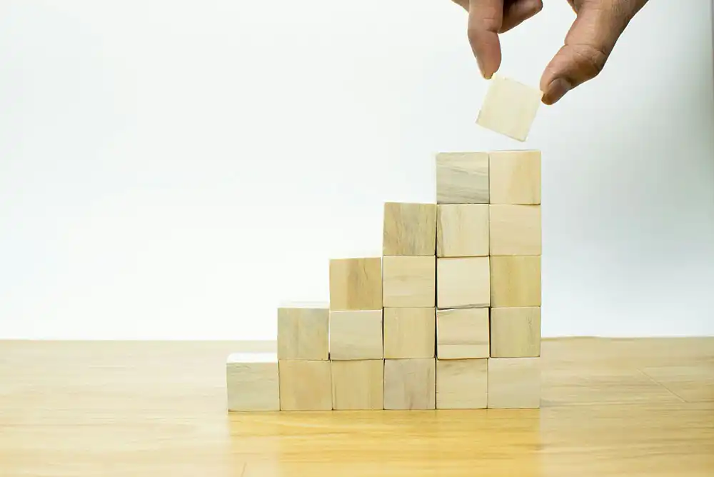 a person is placing wooden blocks on top of an inclined step pyramid