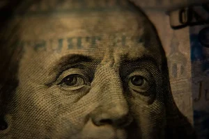 Closeup of a one hundred dollar bill, focusing on the eyes of Benjamin Franklin