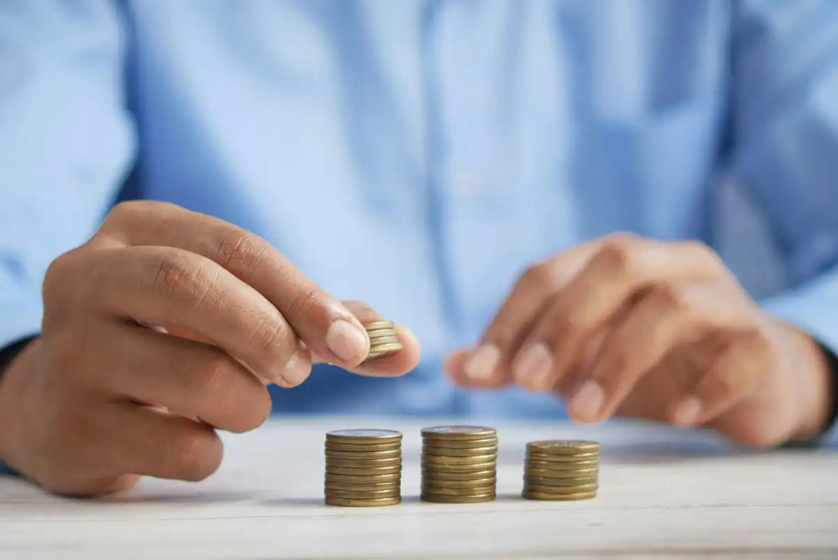 A person stacking coins on top of a table.